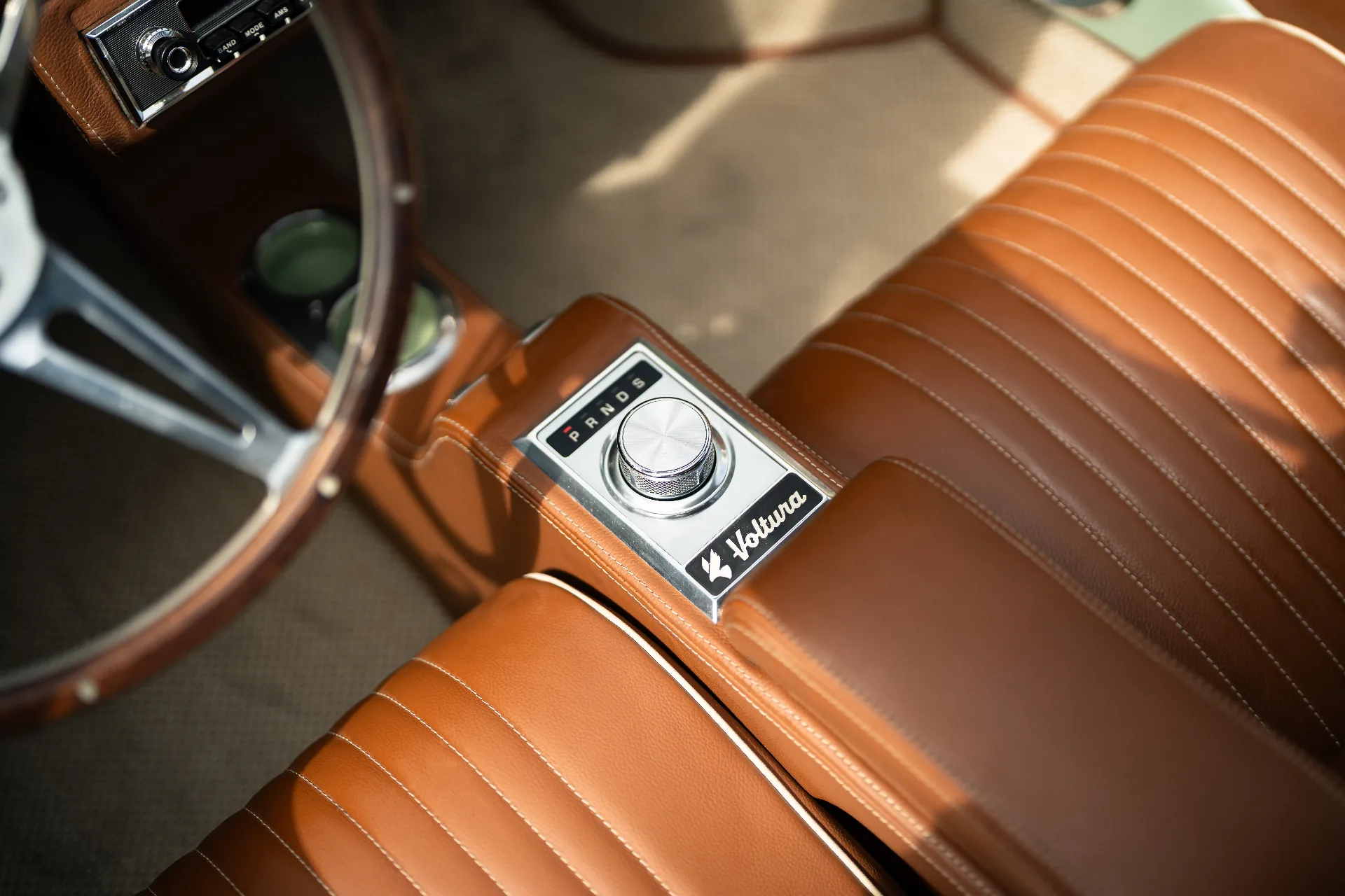 Chrome PRNDS rotary shifter on tan leather console with Voltura badge